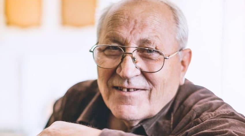 Close up of elderly hands resting on a cane.